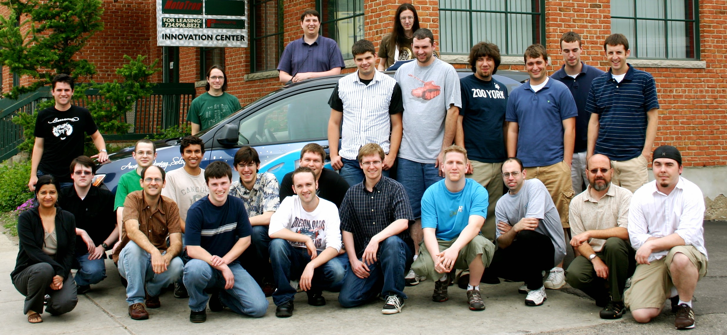 The Barracuda Ann Arbor R&D team gathered outside the Innovation Center building, around a Barracuda-branded car