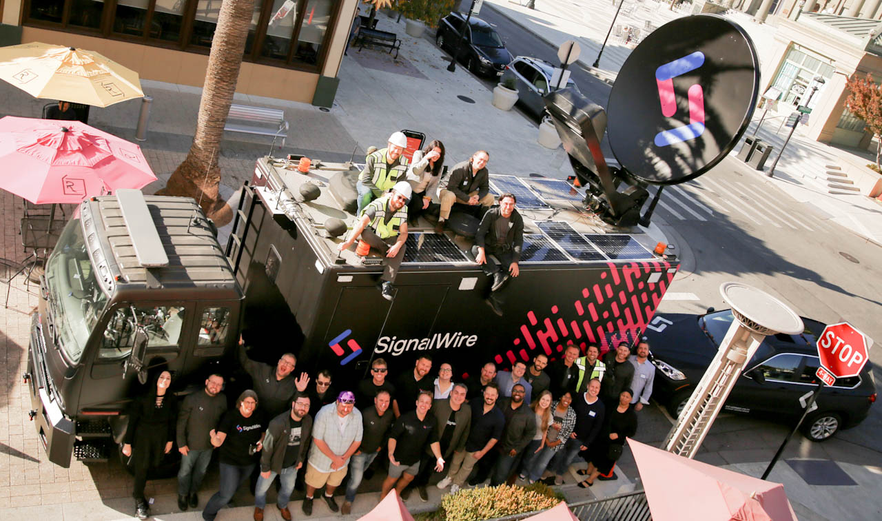 The SignalWire team gathered around and on top of the Mobile Command Center truck, with its satellite dish raised